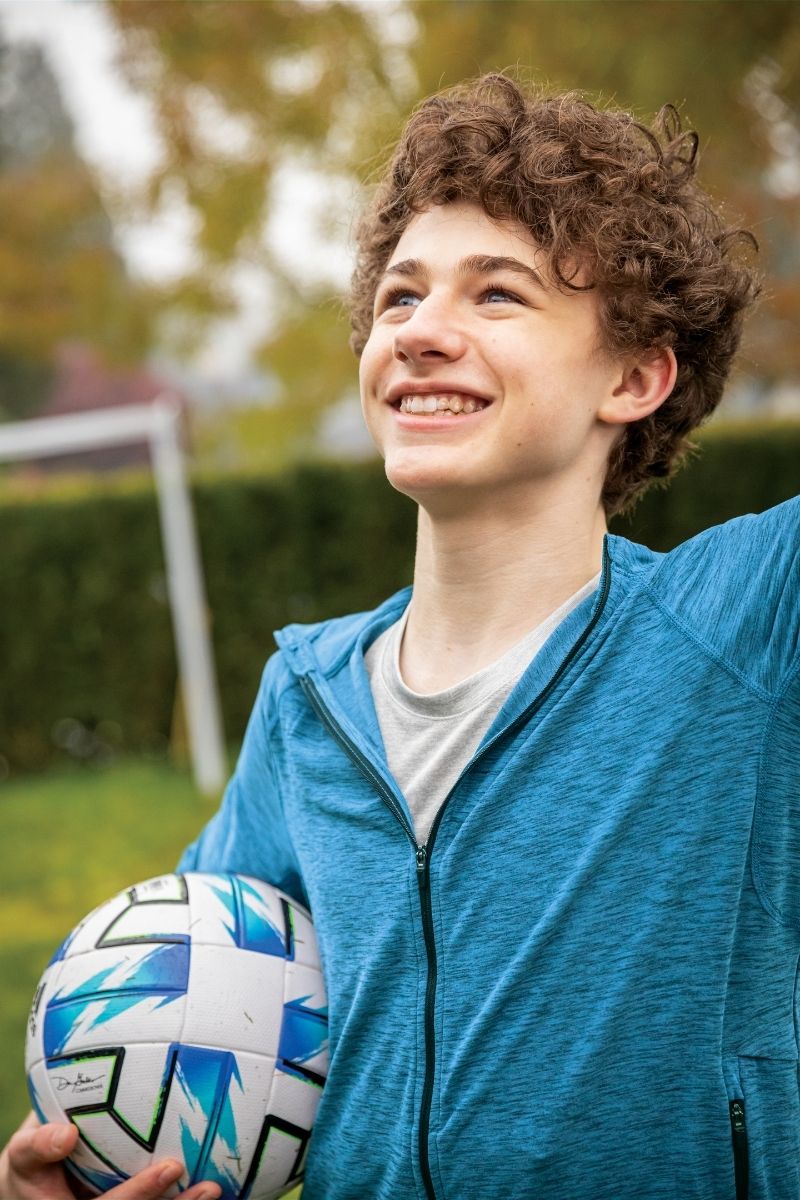 Teen boy with football gear smiling — Invisalign fits active lifestyles without interrupting sports