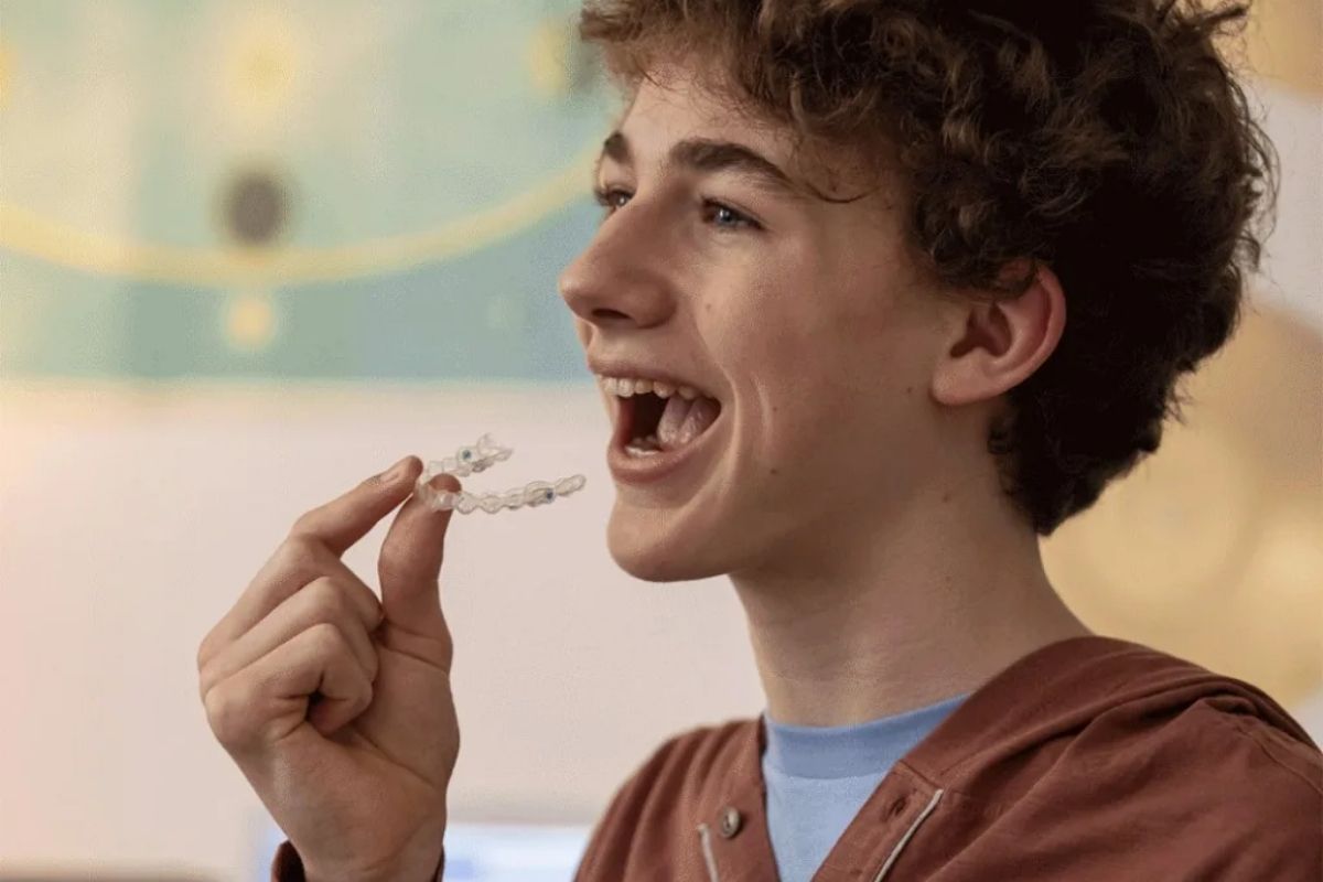 Teenage boy inserting a clear Invisalign aligner — discreet orthodontic treatment that fits a teen lifestyle