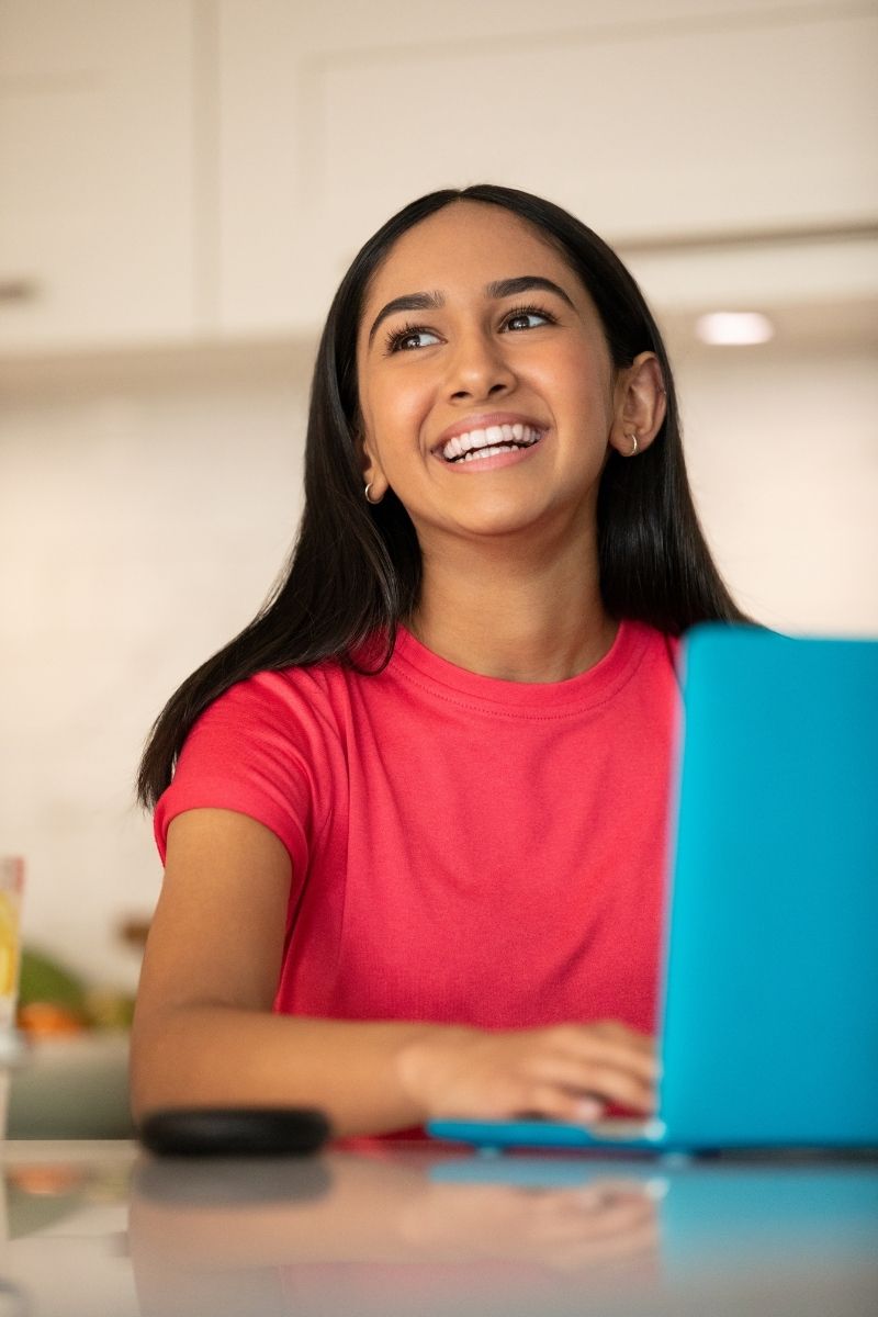 Teenage girl smiling confidently at her desk — trusting her specialist orthodontist for the best treatment outcome