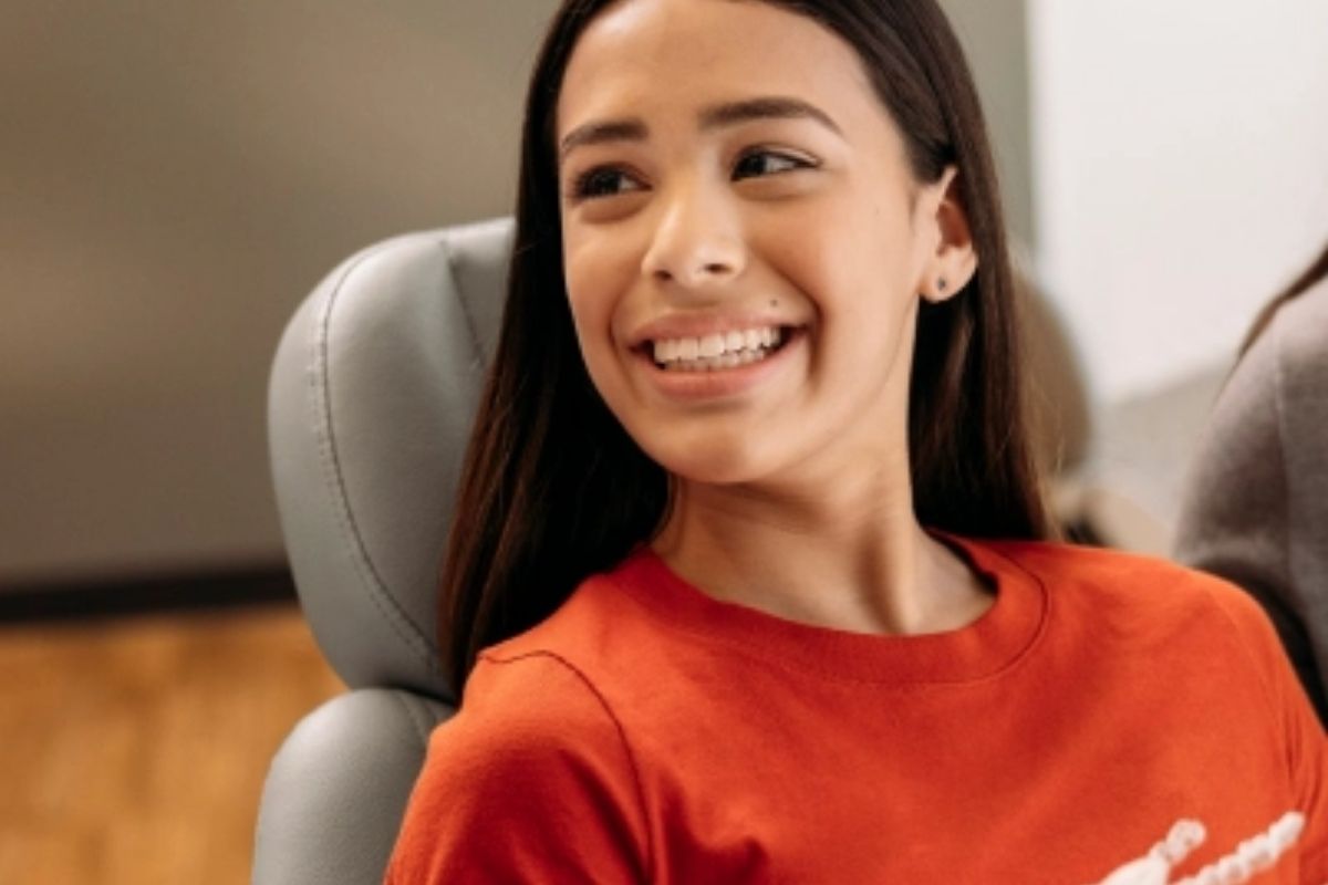 Teenage girl smiling confidently in the orthodontic chair during her Invisalign check-up — comfortable treatment experience